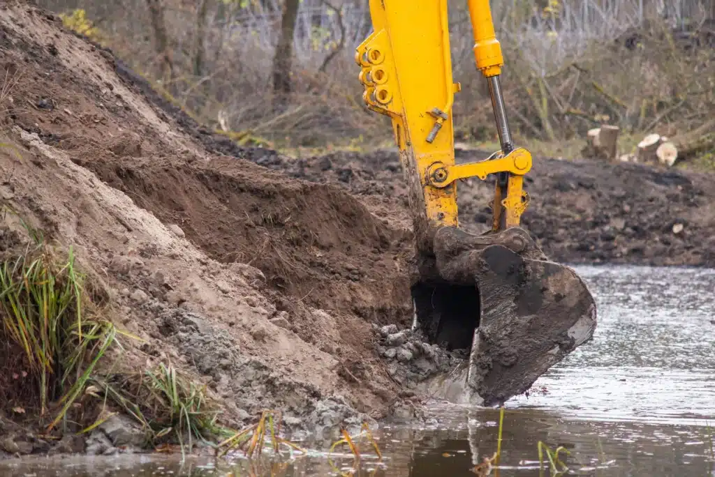Clear Cut Heavy Brush Mulching excavator bucket shaping a pond bank during a pond building and excavation project near Tampa, FL